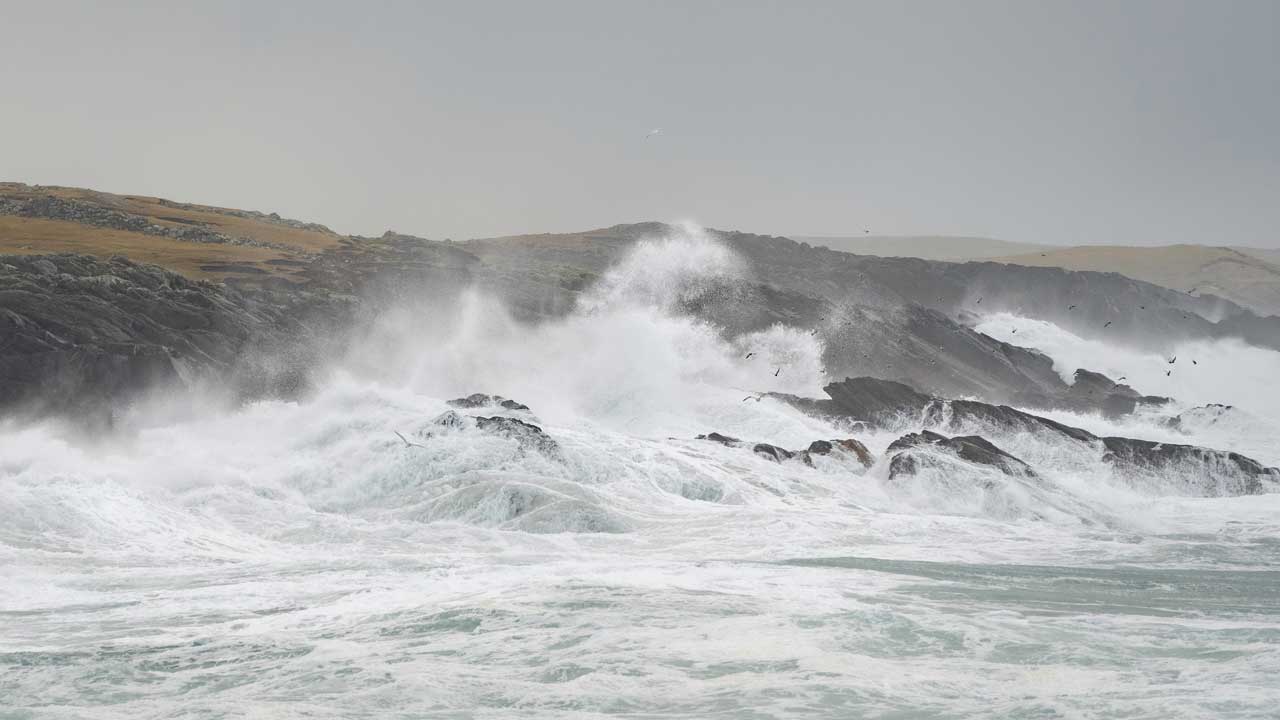 White waves crash against a rugged coastline