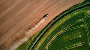Aerial view of tractor ploughing dry, brown field